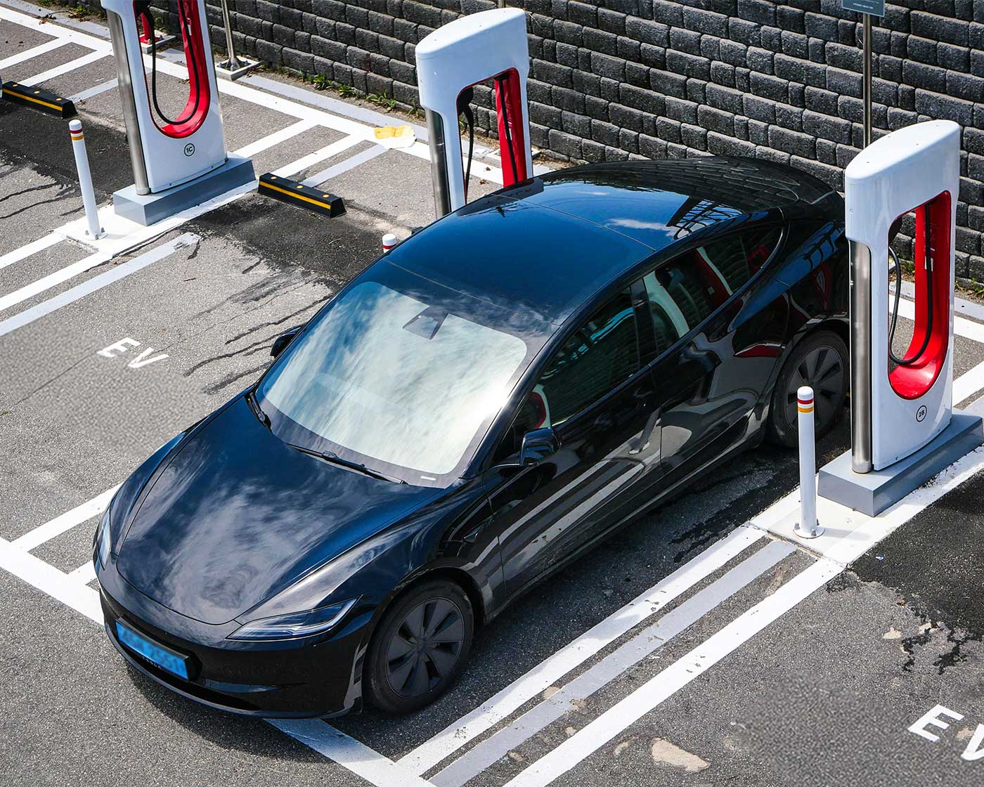 Svart elbil laddas vid nyinstallerad laddstation på parkeringsplats