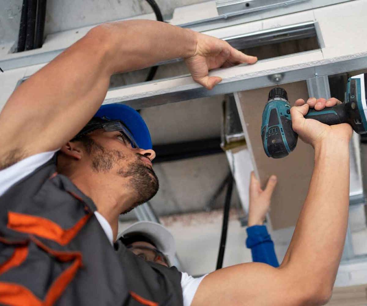 Elektriker arbetar med ventilationsrör i tak för energieffektivisering