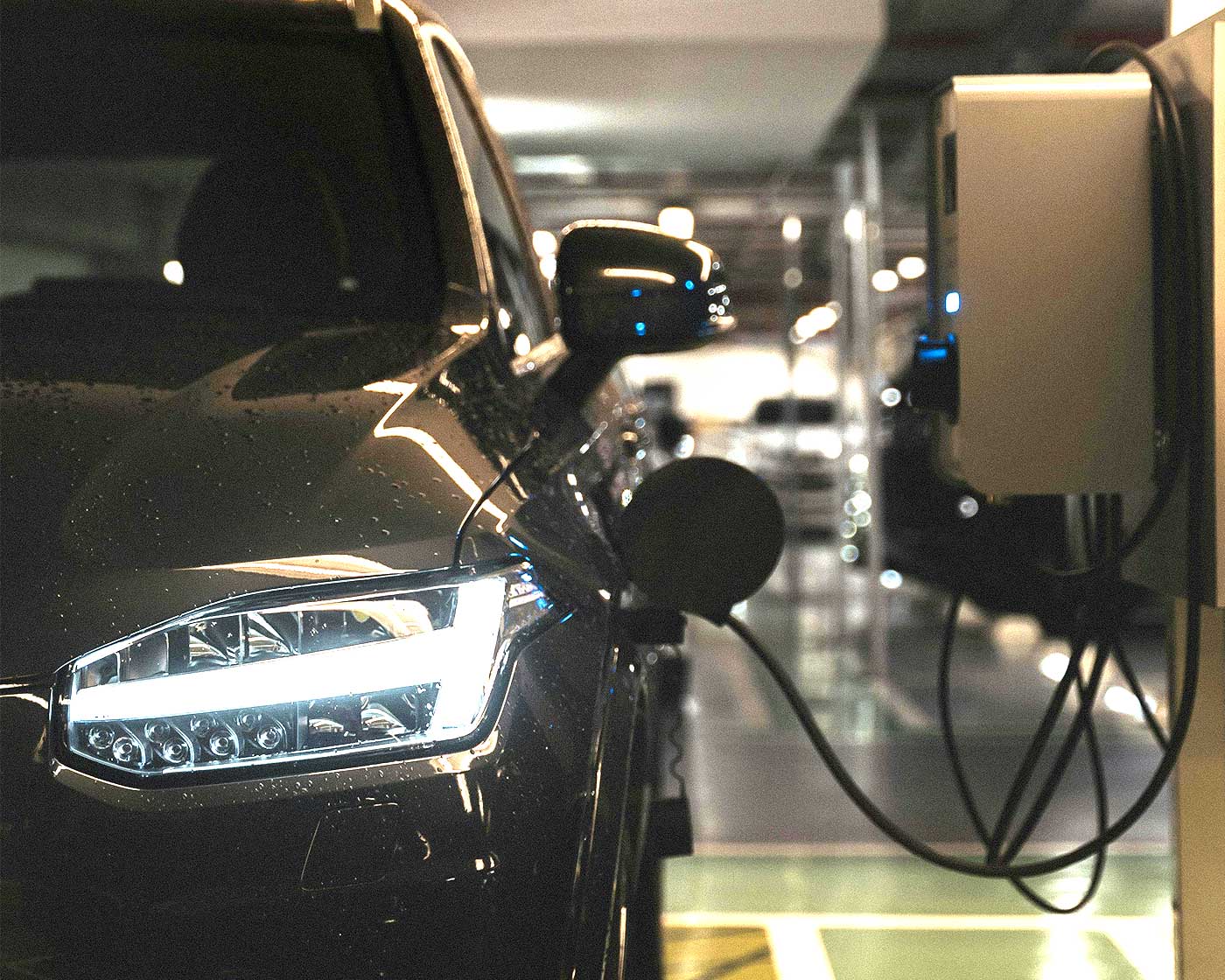 Elbil laddas i underjordiskt garage med väggmonterad laddare