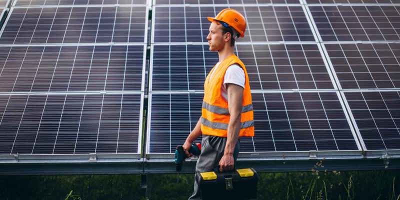Tekniker i skyddsväst framför solpaneler för energieffektivisering