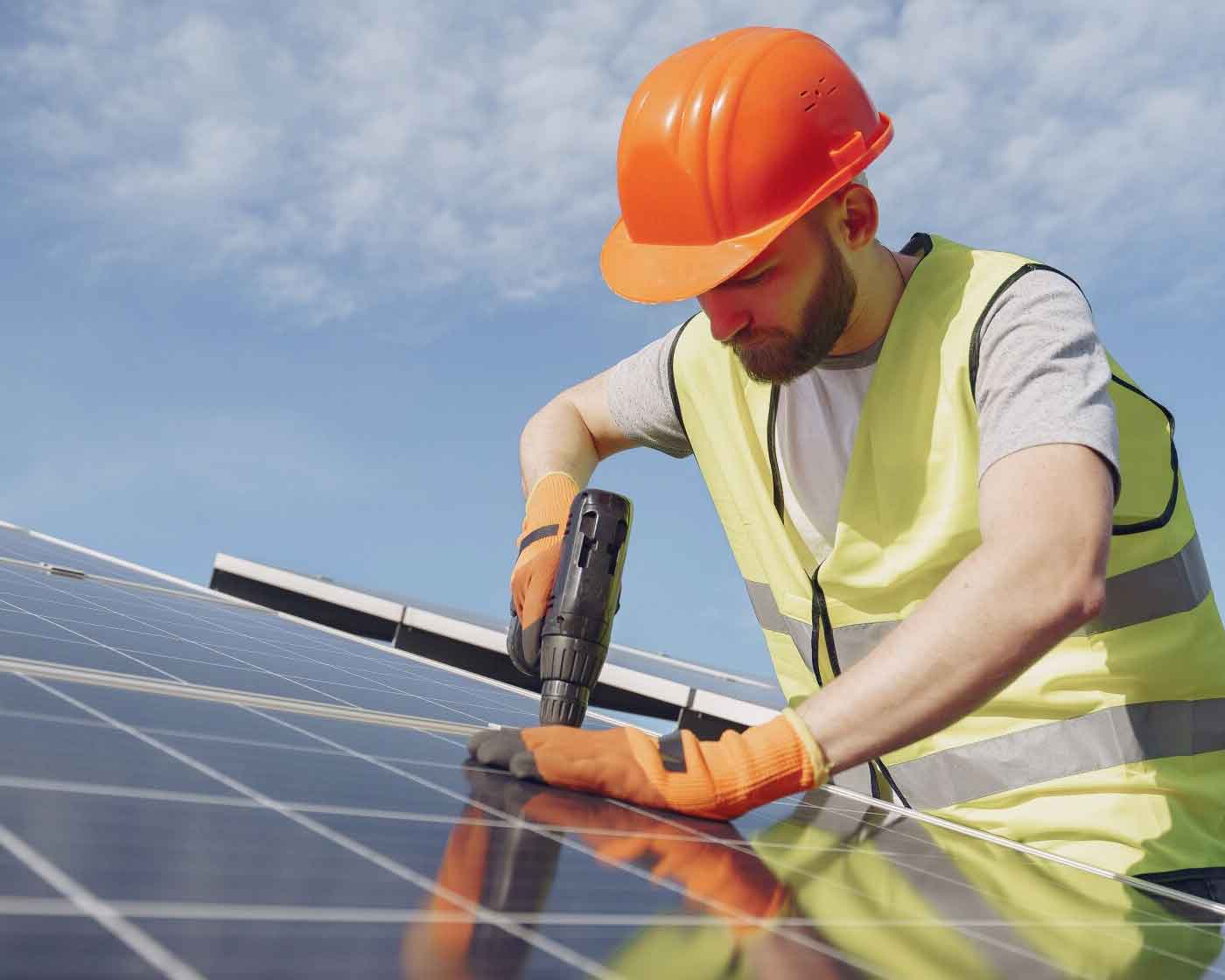 Installatör monterar solcellspanel med borrmaskin under klar himmel