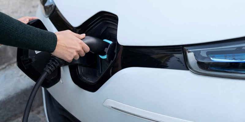 Kvinna som laddar sin elbil hemma med väggmonterad laddstation