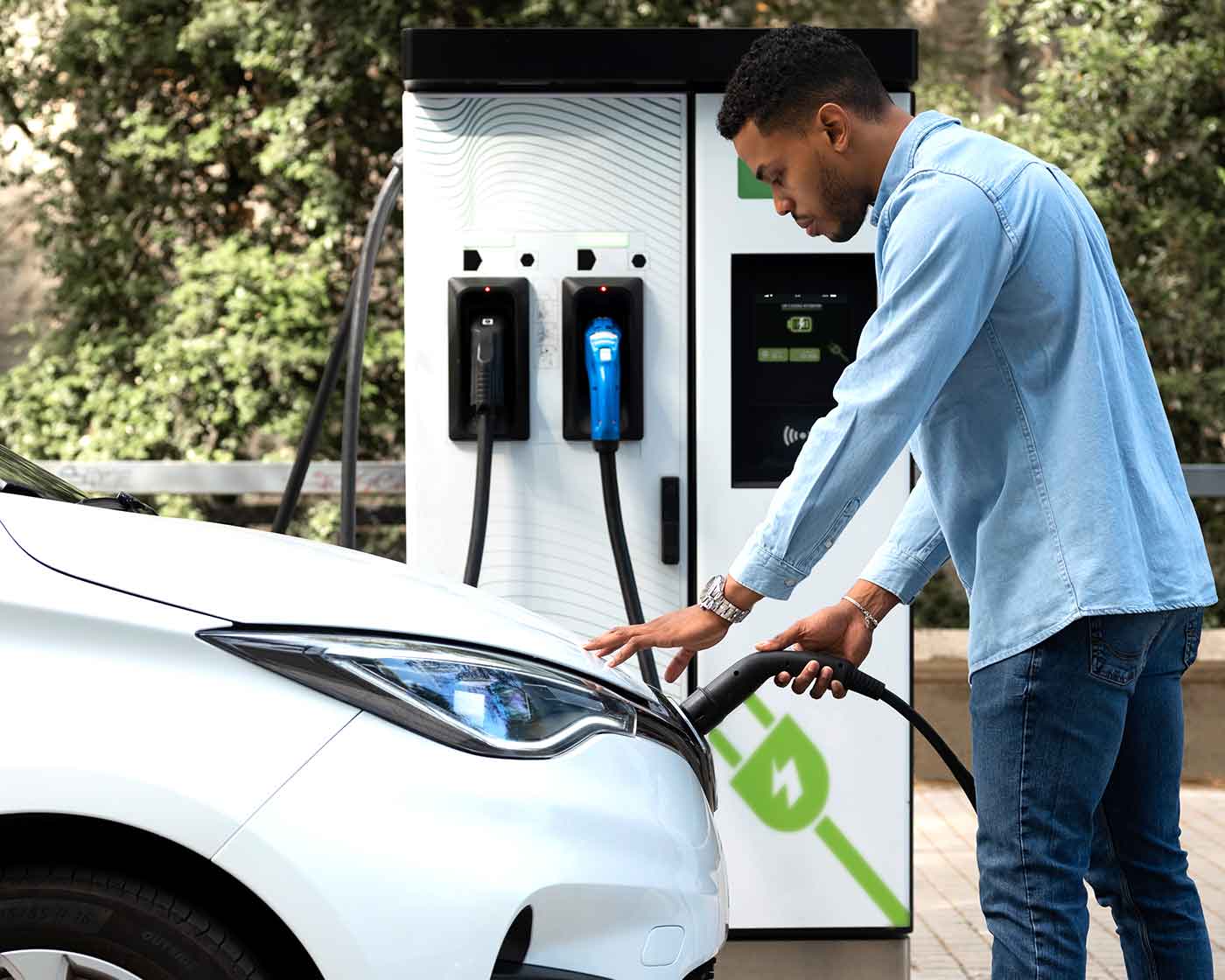 Man som laddar elbil vid publik laddstation i Falköping