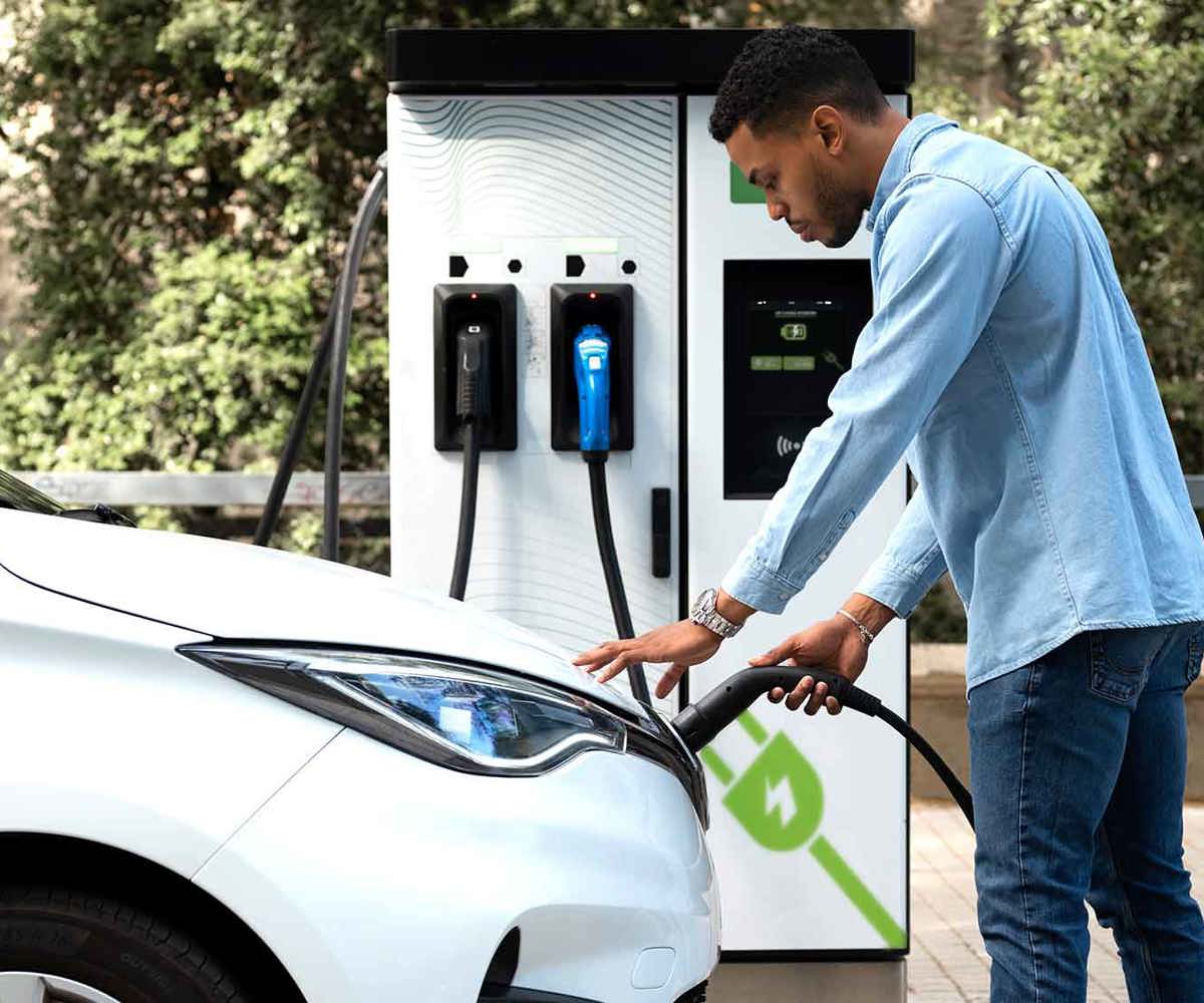 Man som laddar elbil vid publik laddstation i Falköping