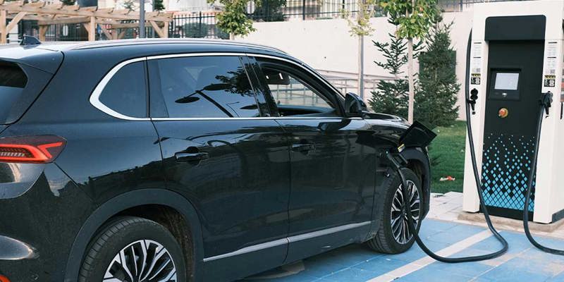 Man laddar elbil vid laddstolpe utanför sitt hem