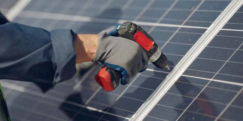 Närbild på installation av solcell med elverktyg och handskar