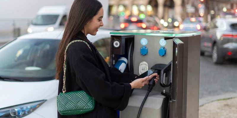 Kvinna laddar elbil vid publik laddstation i centrala Ljungby